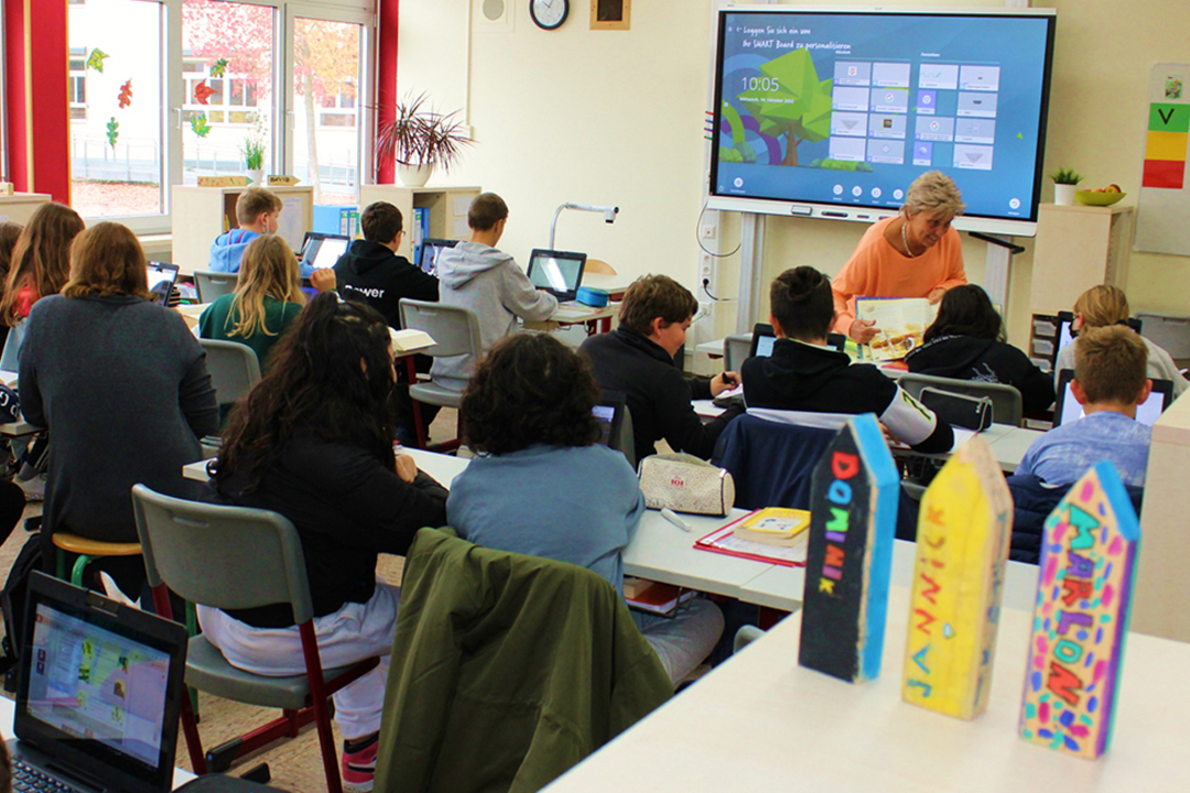 Lehrerin und Schüler*innen im Klassenzimmer beim Unterricht